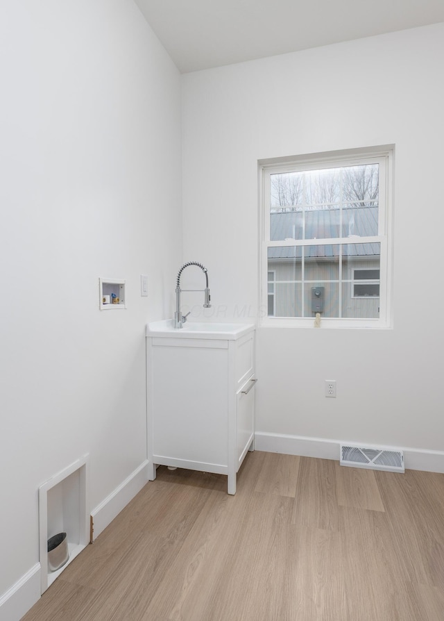 laundry room with hookup for a washing machine, light wood-type flooring, laundry area, and visible vents