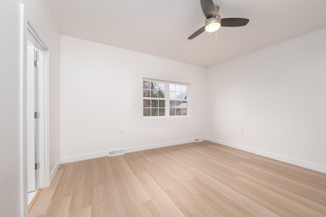 spare room with ceiling fan, light wood-type flooring, visible vents, and baseboards