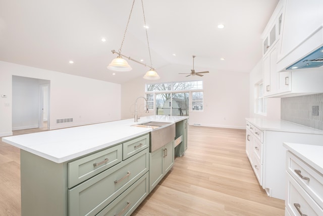 kitchen featuring visible vents, light countertops, light wood-style floors, white cabinetry, and a sink