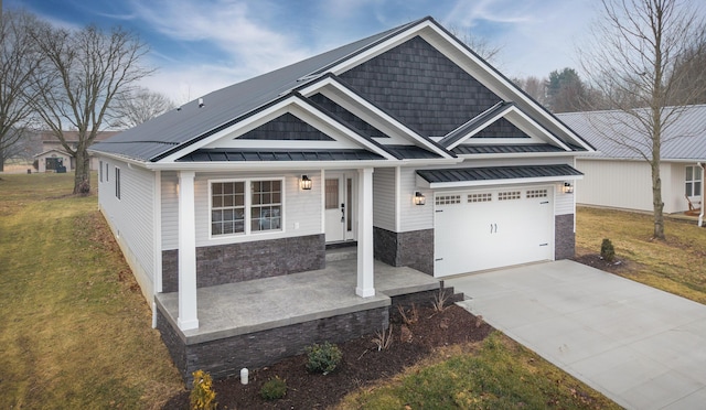 craftsman-style home with an attached garage, stone siding, driveway, a front lawn, and a standing seam roof