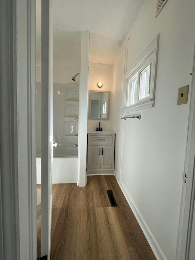 corridor with visible vents, dark wood-style flooring, baseboards, and a sink