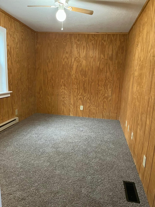 carpeted spare room featuring wooden walls, visible vents, and ceiling fan