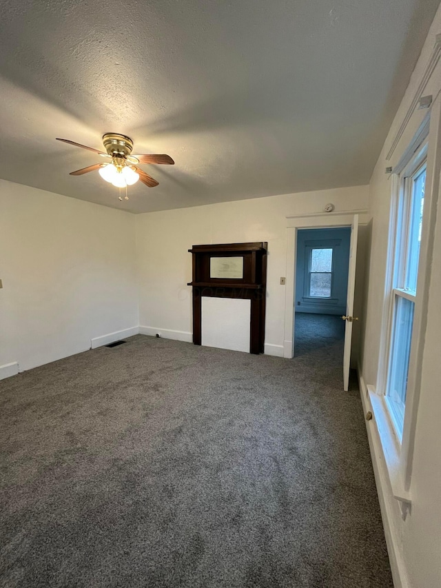 unfurnished living room with visible vents, a textured ceiling, a ceiling fan, and carpet floors