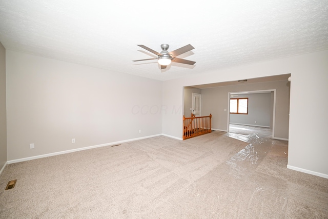 spare room featuring a ceiling fan, light carpet, a textured ceiling, and baseboards