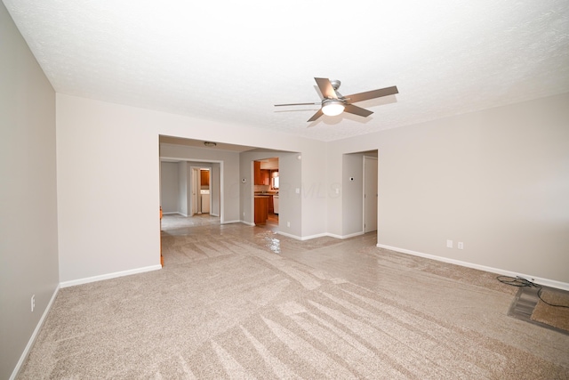 empty room featuring baseboards, a textured ceiling, a ceiling fan, and light colored carpet