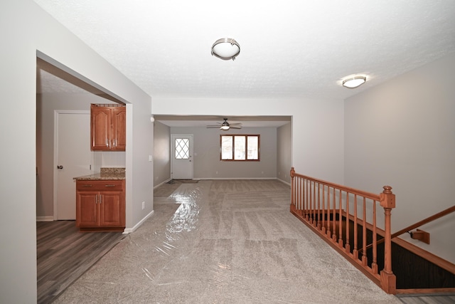 entrance foyer featuring light carpet, ceiling fan, baseboards, and a textured ceiling