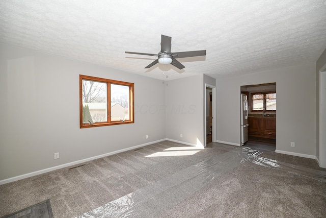 carpeted spare room with a ceiling fan, a textured ceiling, and baseboards