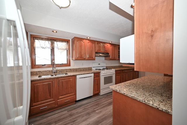 kitchen featuring white appliances, light stone counters, dark wood-style flooring, under cabinet range hood, and a sink