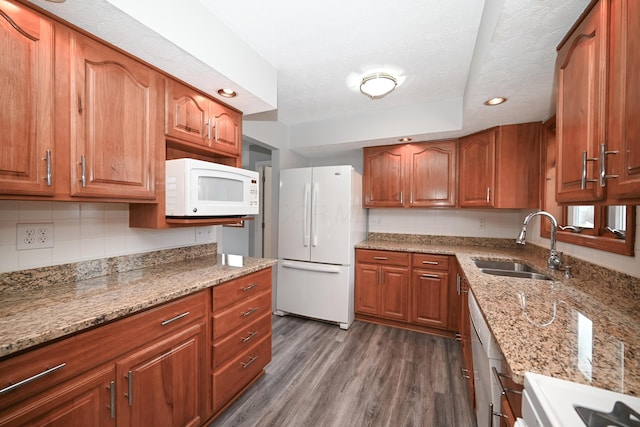 kitchen with white appliances, dark wood-type flooring, a sink, and light stone counters