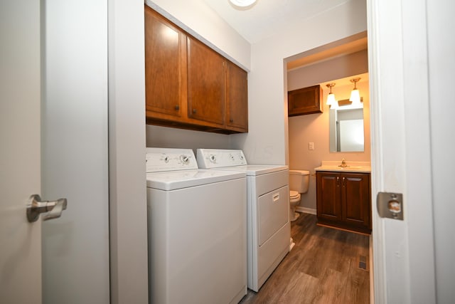 washroom with a sink, separate washer and dryer, dark wood finished floors, and cabinet space