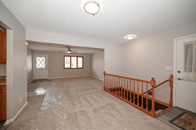 foyer with light carpet, a textured ceiling, and baseboards