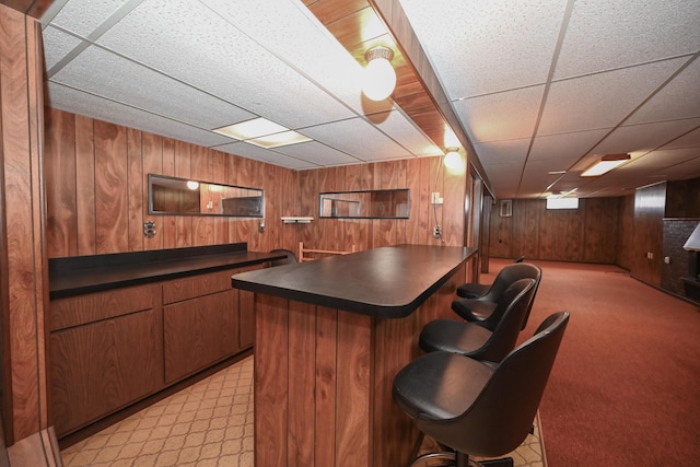 kitchen featuring dark countertops, wooden walls, a kitchen bar, and open floor plan