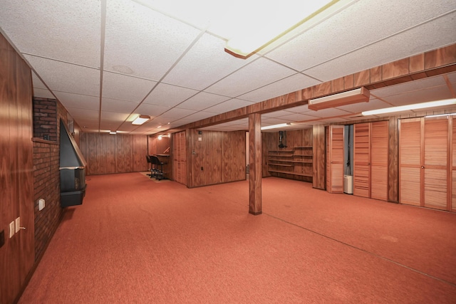 finished below grade area featuring carpet floors, wood walls, and a paneled ceiling