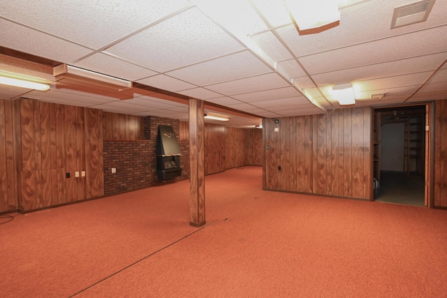 finished below grade area featuring carpet floors, a paneled ceiling, visible vents, and wooden walls