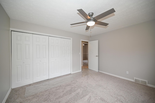 unfurnished bedroom featuring a textured ceiling, a closet, visible vents, and carpet flooring