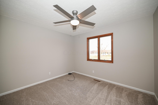 carpeted spare room featuring a textured ceiling, visible vents, and baseboards