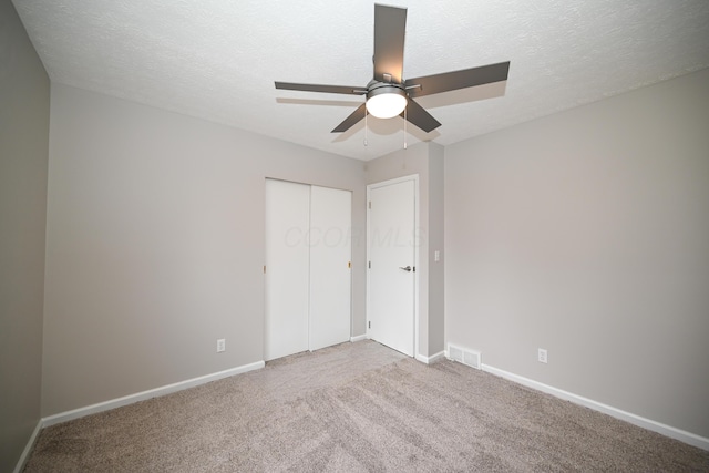 unfurnished bedroom with a textured ceiling, carpet floors, visible vents, and baseboards