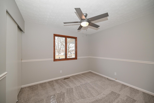 spare room with a textured ceiling, carpet flooring, visible vents, and baseboards