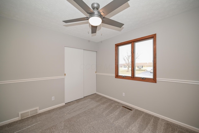 unfurnished bedroom with a textured ceiling, carpet floors, a closet, and visible vents