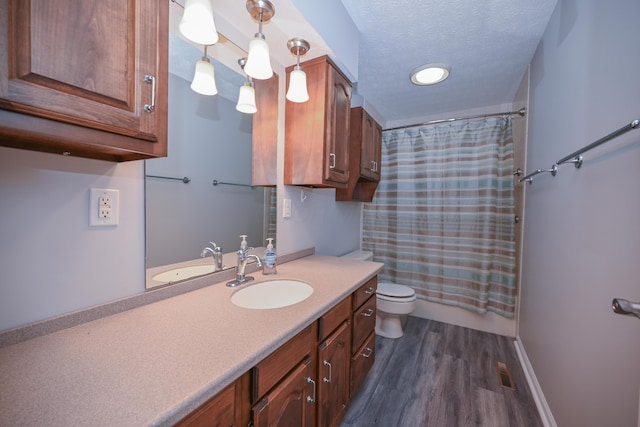 bathroom with visible vents, toilet, a textured ceiling, vanity, and wood finished floors