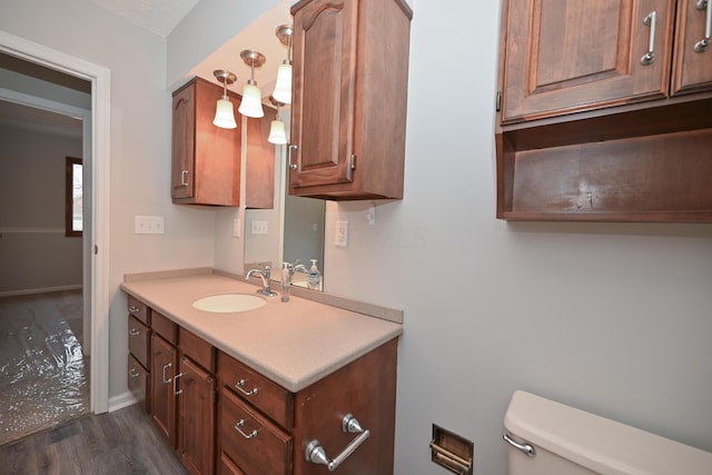 half bath featuring toilet, baseboards, wood finished floors, and vanity