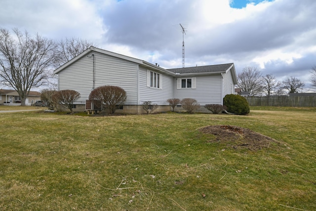 view of side of home with a yard and fence