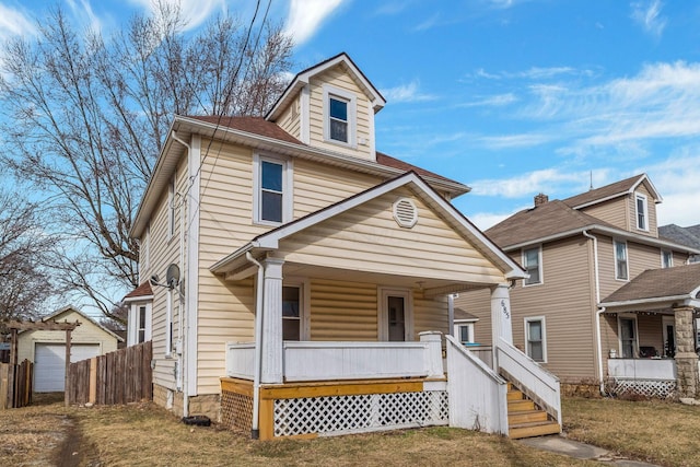 american foursquare style home with a garage, covered porch, and an outbuilding