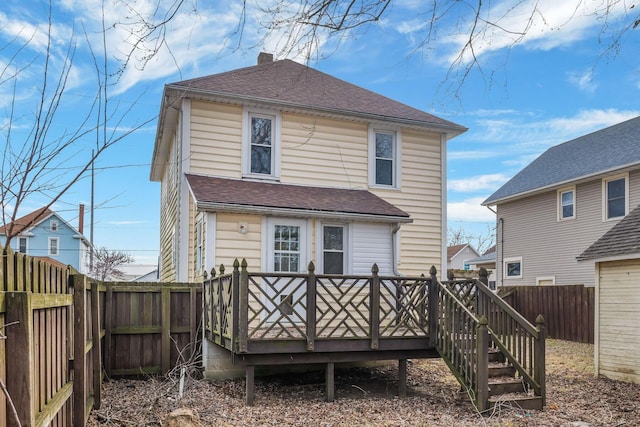 rear view of property with a fenced backyard, a chimney, a wooden deck, and roof with shingles