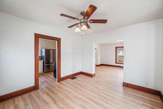 unfurnished room with visible vents, a ceiling fan, light wood-style flooring, and baseboards