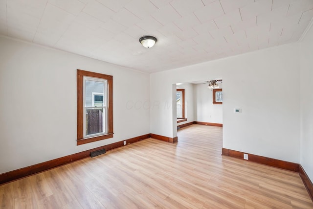 unfurnished room featuring light wood finished floors, visible vents, and baseboards