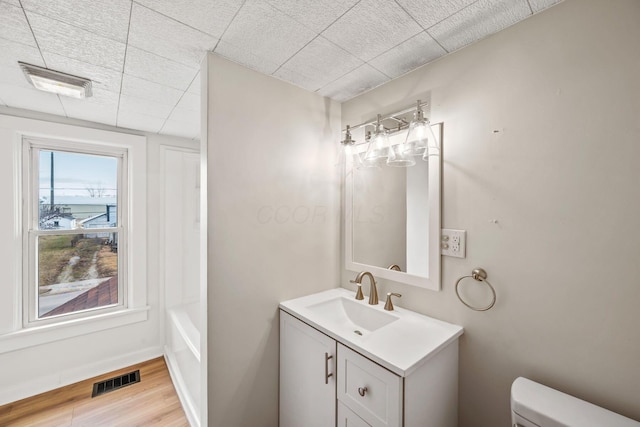 bathroom with toilet, visible vents, wood finished floors, and vanity