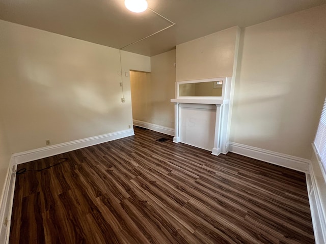 spare room featuring baseboards and dark wood-style flooring