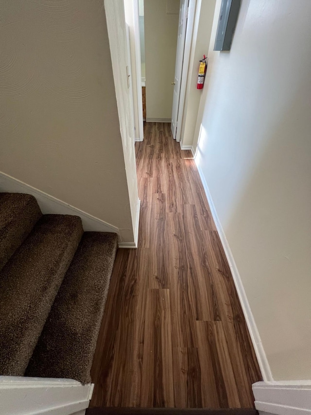 corridor with stairway, wood finished floors, and baseboards