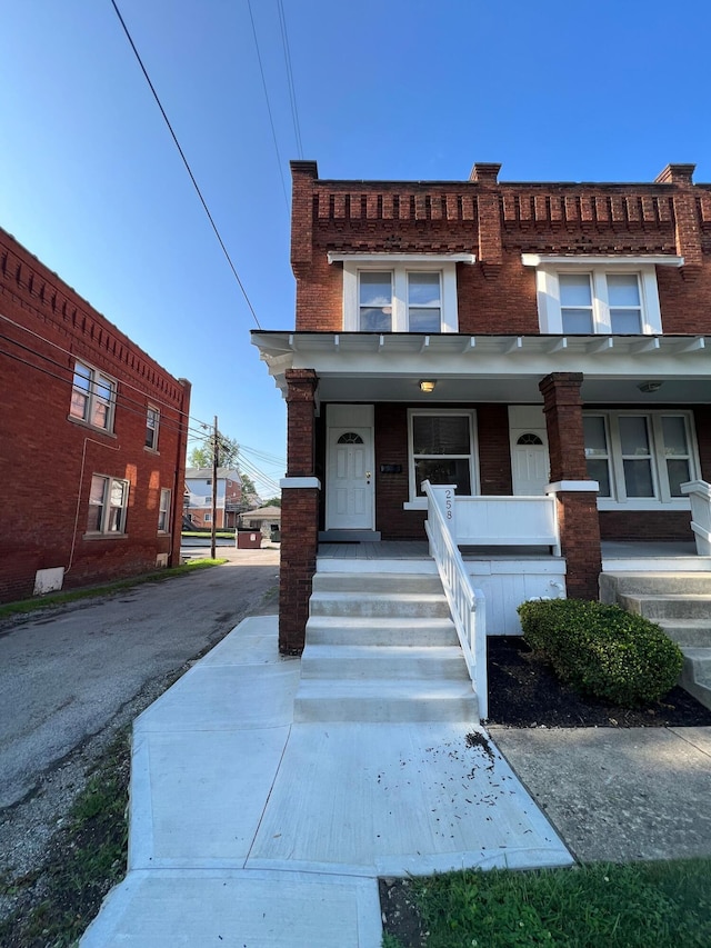 townhome / multi-family property featuring a porch and brick siding