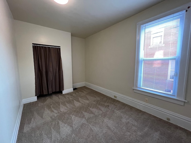 unfurnished room featuring carpet floors and baseboards