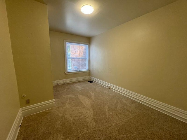 empty room with carpet flooring, visible vents, and baseboards