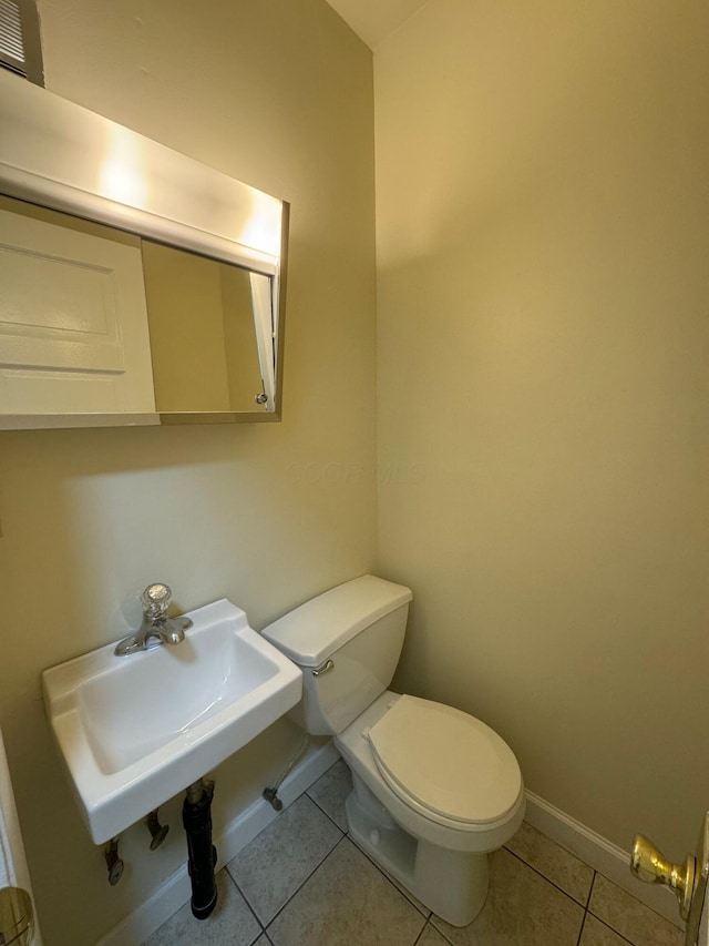 bathroom with baseboards, a sink, toilet, and tile patterned floors