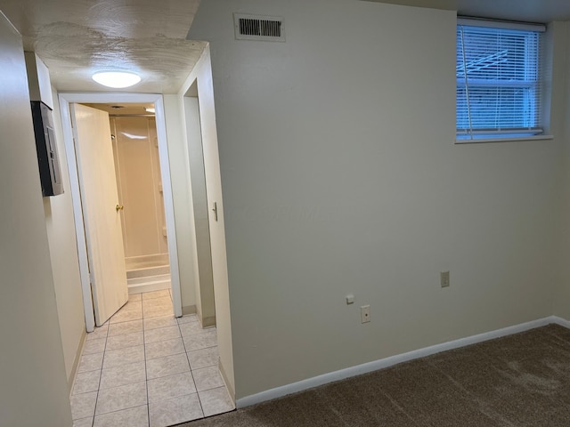 hallway with visible vents, light carpet, baseboards, and light tile patterned floors