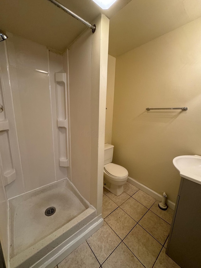 full bath with toilet, vanity, baseboards, a shower stall, and tile patterned floors