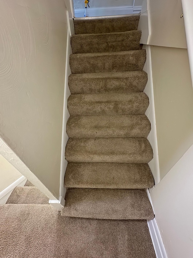 staircase with baseboards and carpet flooring