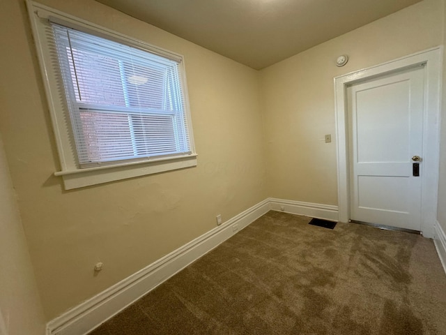 empty room featuring baseboards and dark colored carpet