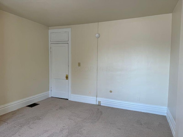 unfurnished room featuring carpet flooring, visible vents, and baseboards