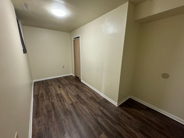 unfurnished room featuring dark wood-style flooring and baseboards