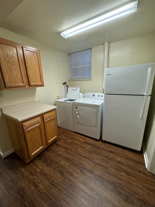 clothes washing area featuring cabinet space, a textured ceiling, washer and clothes dryer, and dark wood-type flooring