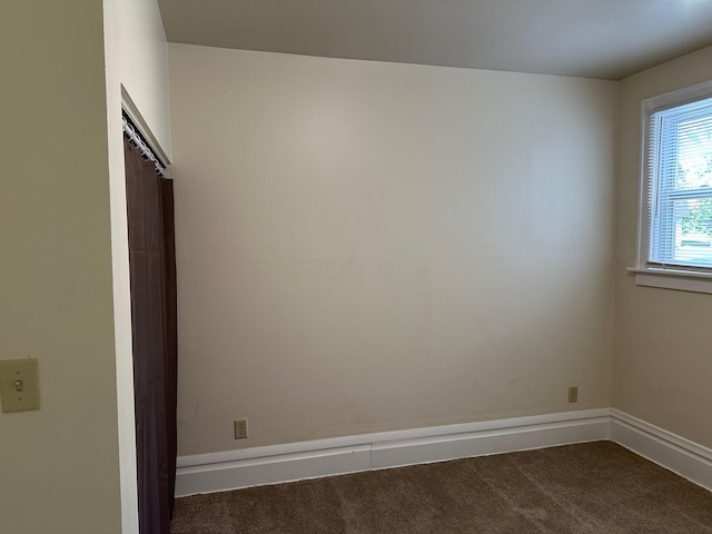 spare room with dark carpet