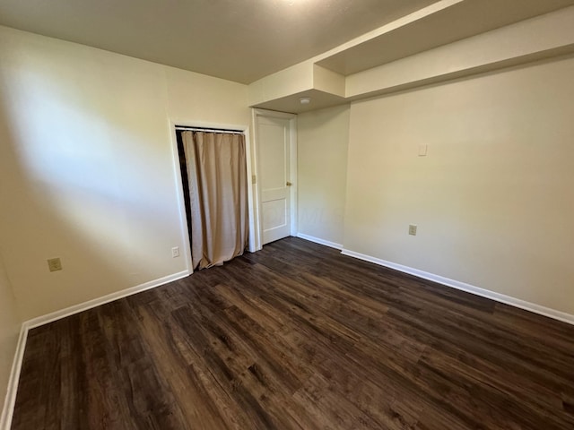 unfurnished bedroom with dark wood-style flooring and baseboards