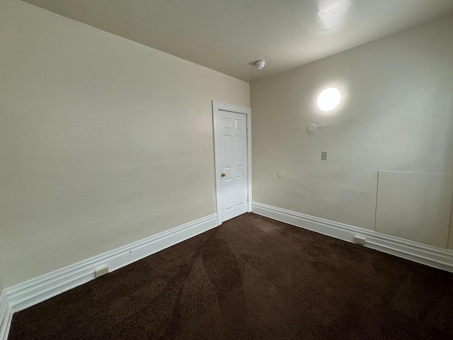 unfurnished room with dark colored carpet and baseboards