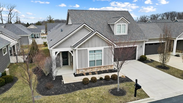 view of front of house with board and batten siding, fence, a garage, stone siding, and driveway