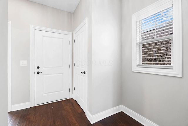 doorway featuring dark wood-style flooring and baseboards