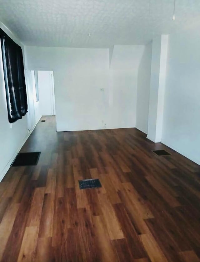 unfurnished living room featuring a textured ceiling and wood finished floors